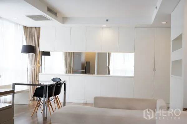 คอนโด ให้เช่าในPathum Wan, Bangkok - พื้นที่นั่งเล่นแบบเปิดโล่ง พร้อมตู้บิวท์อินสีขาว กระจกยาว โซฟาสีครีม และแสงธรรมชาติ