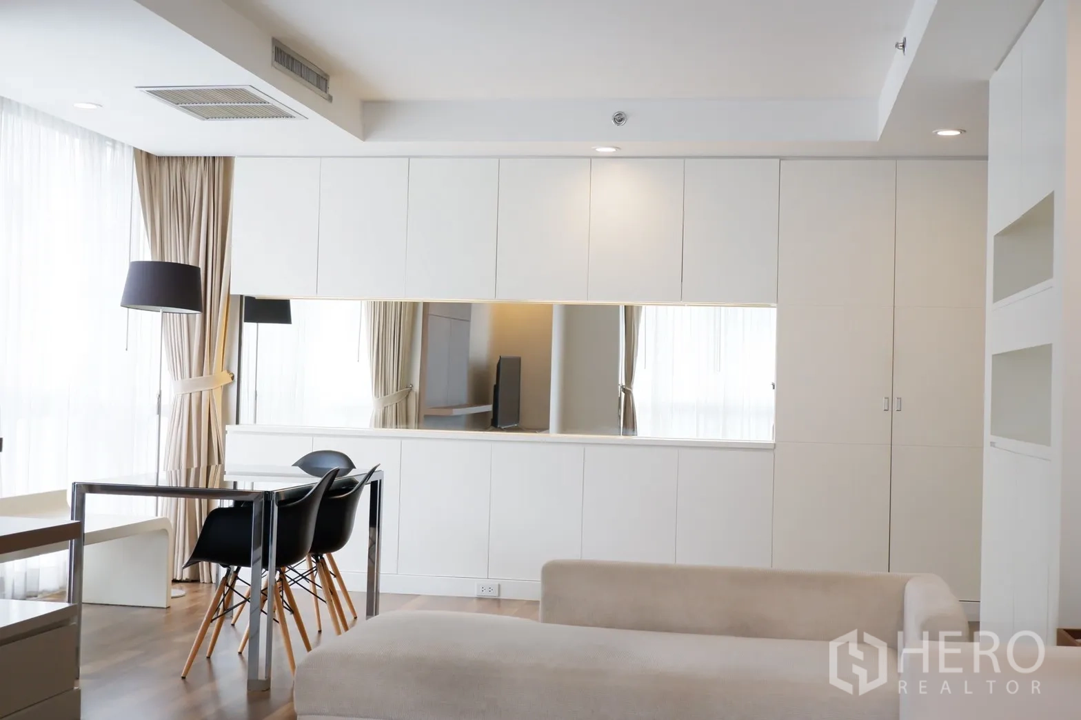 คอนโด ให้เช่าในPathum Wan, Bangkok - พื้นที่นั่งเล่นแบบเปิดโล่ง พร้อมตู้บิวท์อินสีขาว กระจกยาว โซฟาสีครีม และแสงธรรมชาติ