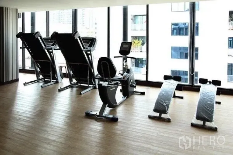 คอนโด ให้เช่าหรือขายในPathum Wan, Bangkok - ห้องฟิตเนสของคอนโดพร้อมลู่วิ่ง จักรยาน และม้านั่งซิตอัพ ข้างหน้าต่างบานใหญ่เห็นวิวเมือง
