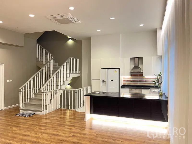 ทาวน์เฮาส์ ให้เช่าในYan Nawa, Bangkok - ครัวร่วมสมัยติดกับบันไดสีขาว มีไฟส่องและเคาน์เตอร์บาร์สีดำเงา