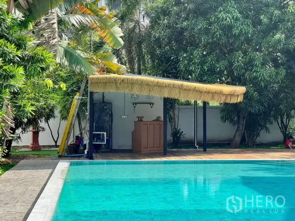 Detached House for sale in Prawet, Bangkok - Pool deck with a thatched-roof bar area set among mature trees.