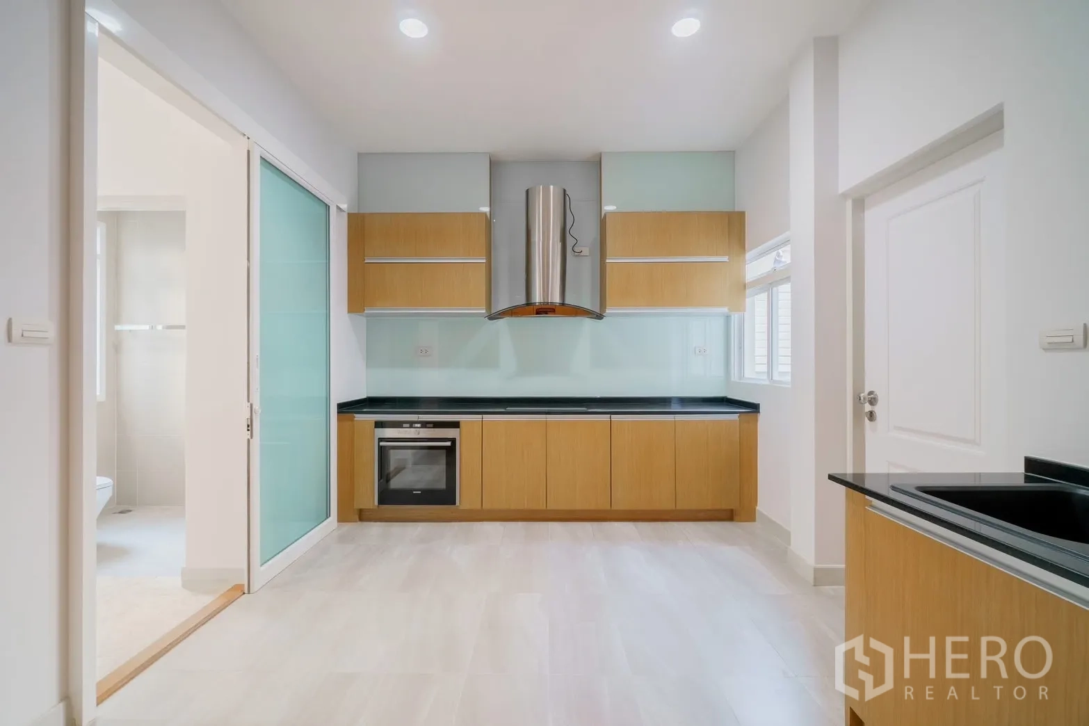 Detached House for rent or sale in Saphan Sung, Bangkok - Modern kitchen with oven, hood and wood cabinetry.