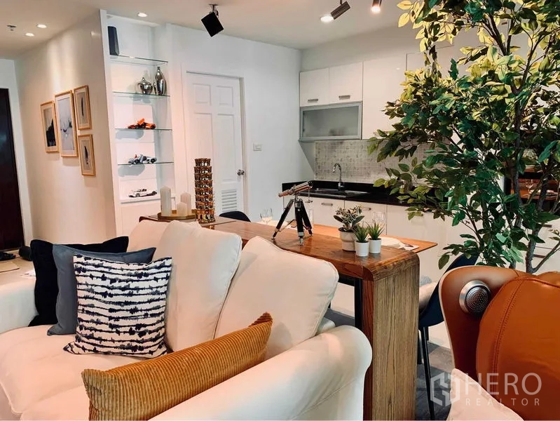 คอนโด ให้เช่าในWatthana, Bangkok - โถงนั่งเล่นและทานอาหารแบบโอเพ่นแปลน โซฟาสีครีม โต๊ะไม้ และครัวด้านหลัง