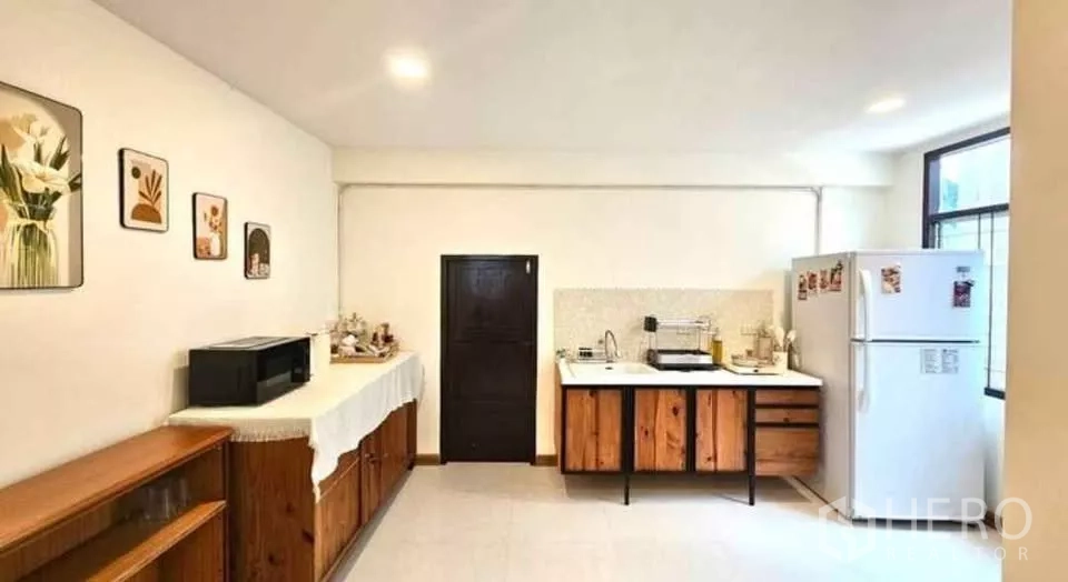 บ้าน ให้เช่าในKhlong Toei, Bangkok - ห้องครัวเรียบง่าย เคาน์เตอร์สีขาว ตู้ล่างไม้ ซิงก์ เตา และตู้เย็น