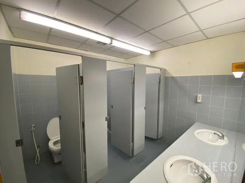 Office Space for rent in Huai Khwang, Bangkok - Restroom view showing stall doors, handheld bidet and twin-sink vanity.