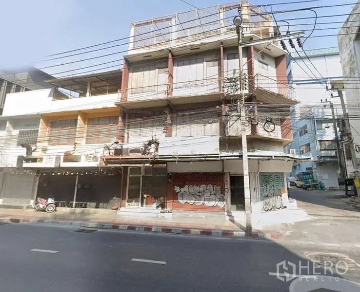 Shophouse for rent in Sathon, Bangkok - Street view of multi-storey corner shophouse with balconies and shuttered shopfronts in Sathon, Bangkok.