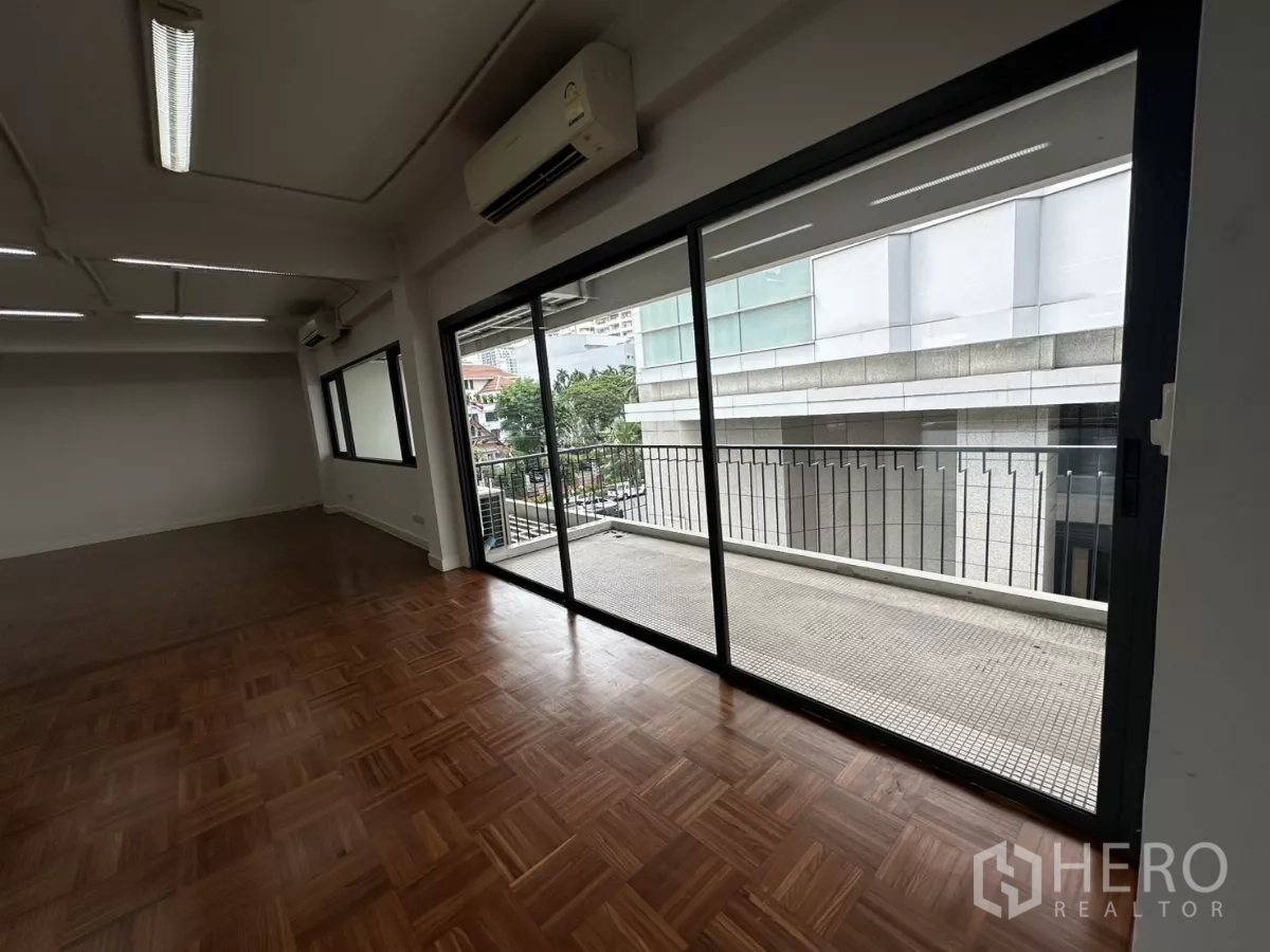 办公空间 出租在Watthana, Bangkok - 办公室一角，推拉落地门连接阳台，可见邻近建筑景观。