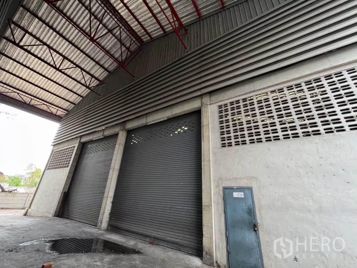 คลังสินค้า ให้เช่าในKhlong Sam Wa, Bangkok - โซนโหลดสินค้าด้านนอกรั้วโรงงาน มีประตูม้วนเหล็กสามบานและชายคา