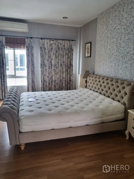 Townhouse for rent in Wang Thonglang, Bangkok - Bedroom angle with tufted bed, feature wall, windows and air conditioner.