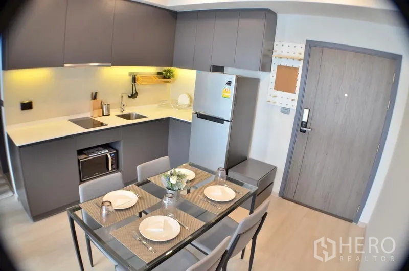 คอนโด ให้เช่าในWatthana, Bangkok - ครัวทันสมัยตู้สีเทา เตาไฟฟ้า ตู้เย็น และโต๊ะอาหาร