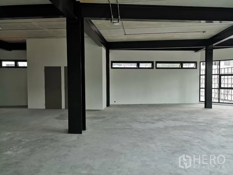 办公空间 出租在Chatuchak, Bangkok - 办公室转角区，带高位横窗、白色墙面与钢结构立柱。