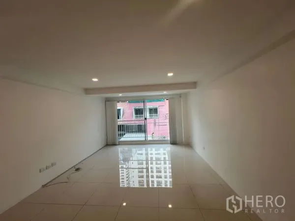 带办公室的家 出租在Khlong Toei, Bangkok - 宽敞白色客厅，筒灯照明，推拉落地门通向阳台。