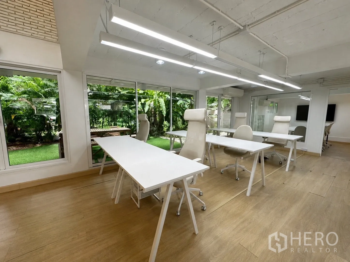 Office Space for rent in Phaya Thai, Bangkok - Bright workspace with white desks facing lush greenery.