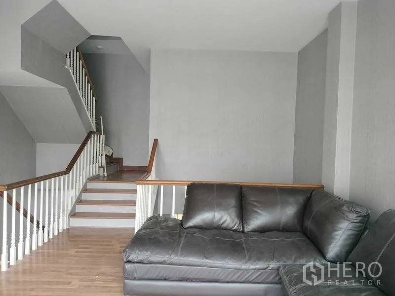 ทาวน์เฮาส์ ให้เช่าในBueng Kum, Bangkok - โถงบันไดพร้อมโซฟาหนัง สีดำ และราวบันไดสีขาว