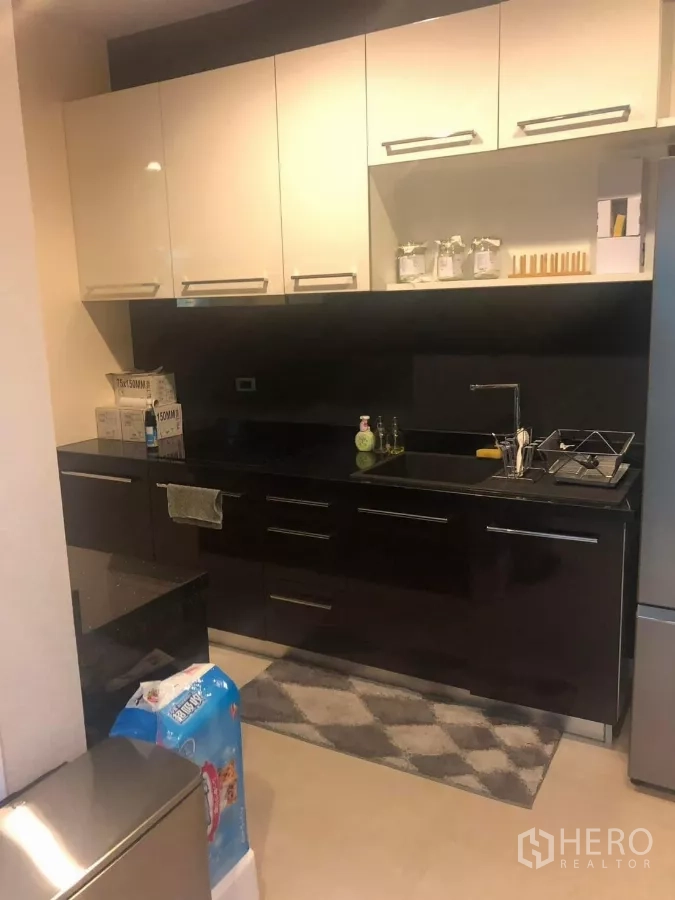 Detached House for rent in Bang Kapi, Bangkok - Sleek kitchen with glossy cabinets, black countertops and sink by refrigerator.