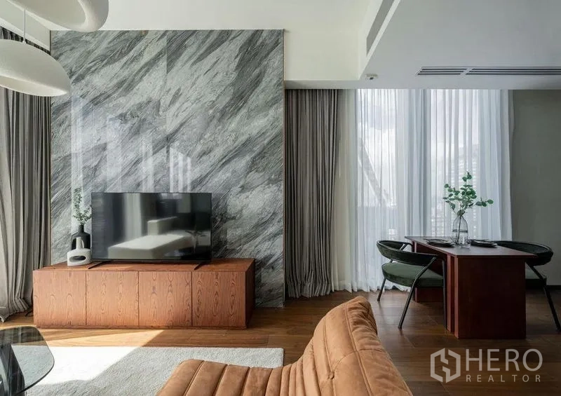公寓 出租在Khlong Toei, Bangkok - 客厅内大理石电视背景墙与用餐角，配轻薄窗帘。