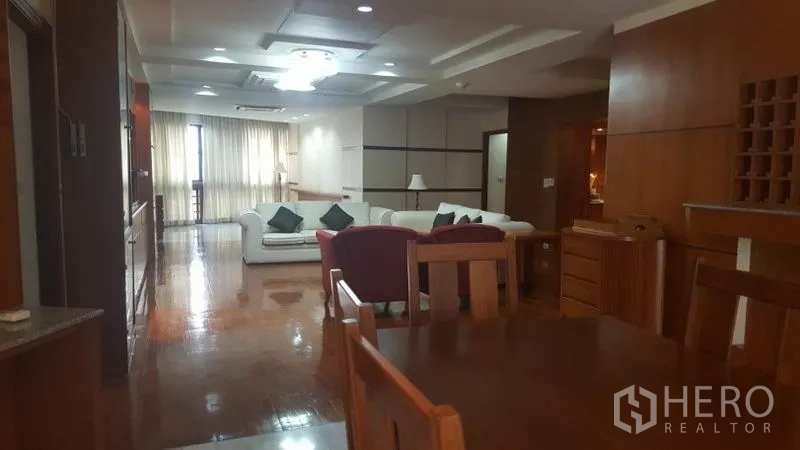 คอนโด ให้เช่าในKhlong Toei, Bangkok - มุมมองจากโต๊ะอาหารไปยังห้องนั่งเล่นยาว พร้อมไฟเพดานและเคาน์เตอร์บาร์