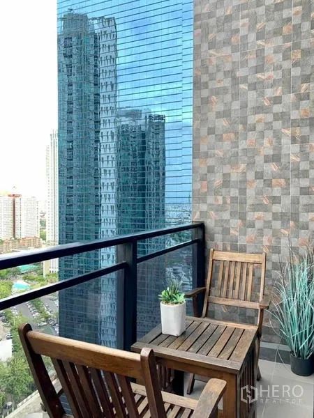 Condominium for rent or sale in Huai Khwang, Bangkok - Balcony with wooden chairs and small plants, showcasing high-rise city views.