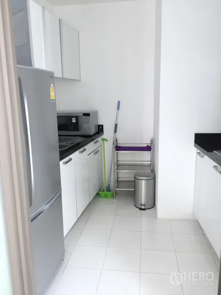 คอนโด ให้เช่าในPathum Wan, Bangkok - ครัวแยกขนาดกะทัดรัด พร้อมตู้เย็น ไมโครเวฟ ตู้เก็บของสีขาว และพื้นกระเบื้อง