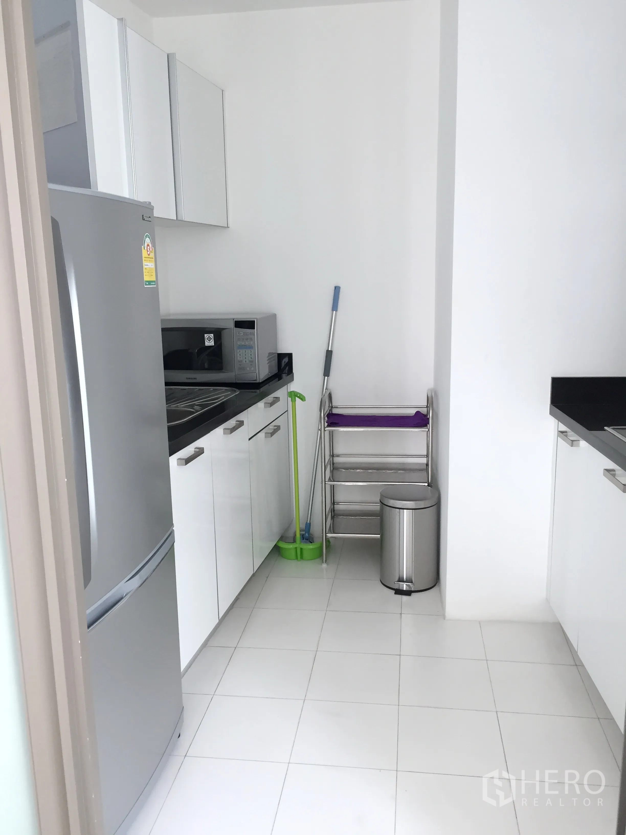 คอนโด ให้เช่าในPathum Wan, Bangkok - ครัวแยกขนาดกะทัดรัด พร้อมตู้เย็น ไมโครเวฟ ตู้เก็บของสีขาว และพื้นกระเบื้อง