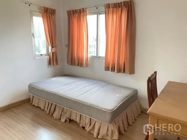 คอนโด ให้เช่าในKhlong Toei, Bangkok - ห้องนอนขนาดกะทัดรัด มีโต๊ะทำงาน หน้าต่างมุมสองด้าน และผ้าม่านสีพีช