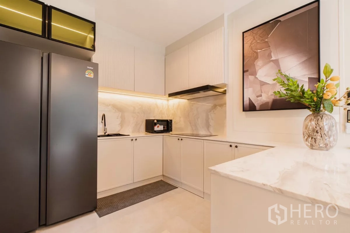 บ้าน ให้เช่าหรือขายในPrawet, Bangkok - ครัวสมัยใหม่รูปตัวแอล ตู้สีขาว ผนังลายหินอ่อน และตู้เย็นสีดำ