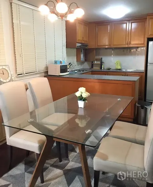 คอนโด ให้เช่าในWatthana, Bangkok - มุมรับประทานอาหารสว่างด้วยโต๊ะกระจกและเก้าอี้บุผ้า ติดกับครัวบิวท์อินไม้ในคอนโด