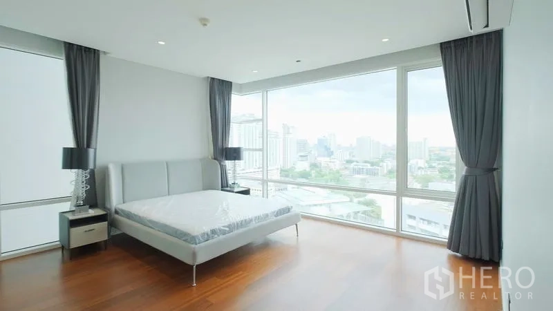 คอนโด ขาย - ห้องนอนใหญ่พร้อมหน้าต่างบานกว้าง เตียงและโต๊ะข้างเตียง