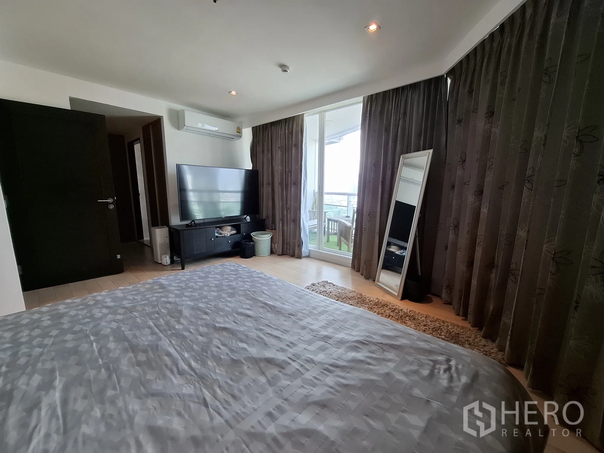 Condominium for rent in Watthana, Bangkok - Primary bedroom with TV console, balcony access, and full-length curtains.