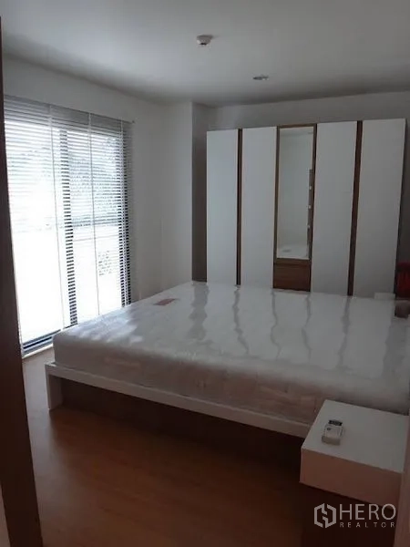 公寓 出租在Bang Rak, Bangkok - 明亮卧室，配有双人床、落地窗百叶及白色衣柜，木地板。