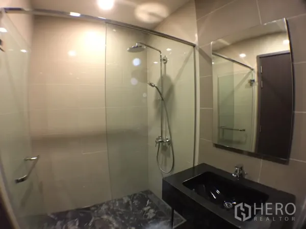 คอนโด ให้เช่าในWatthana, Bangkok - ห้องน้ำสมัยใหม่ มีกระจกกั้นอาบน้ำ ฝักบัวเรนชาวเวอร์ กระจกบานใหญ่ และเคาน์เตอร์หินสีดำ