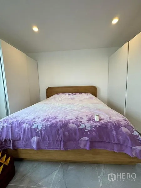 公寓 出租或出售 - 卧室配大床、紫色被套与两侧嵌入衣柜。