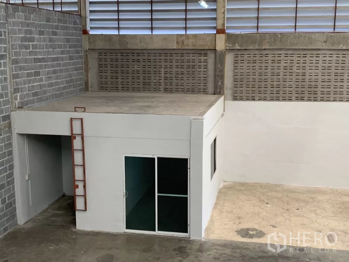 Warehouse for rent in Min Buri, Bangkok - Compact ground-floor office box with rooftop platform and ladder within the warehouse.
