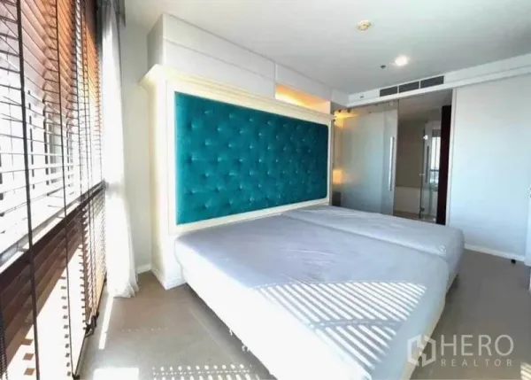 คอนโด ให้เช่าในKhlong San, Bangkok - ห้องนอนรับแสงพร้อมหัวเตียงกำมะหยี่สีเขียวน้ำทะเล และประตูกระจกเข้าสู่ห้องน้ำในตัว