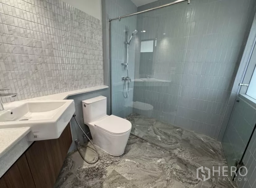 独立式住宅 出租在Watthana, Bangkok - 现代浴室，玻璃淋浴间、灰色瓷砖与悬挂式洗手台。