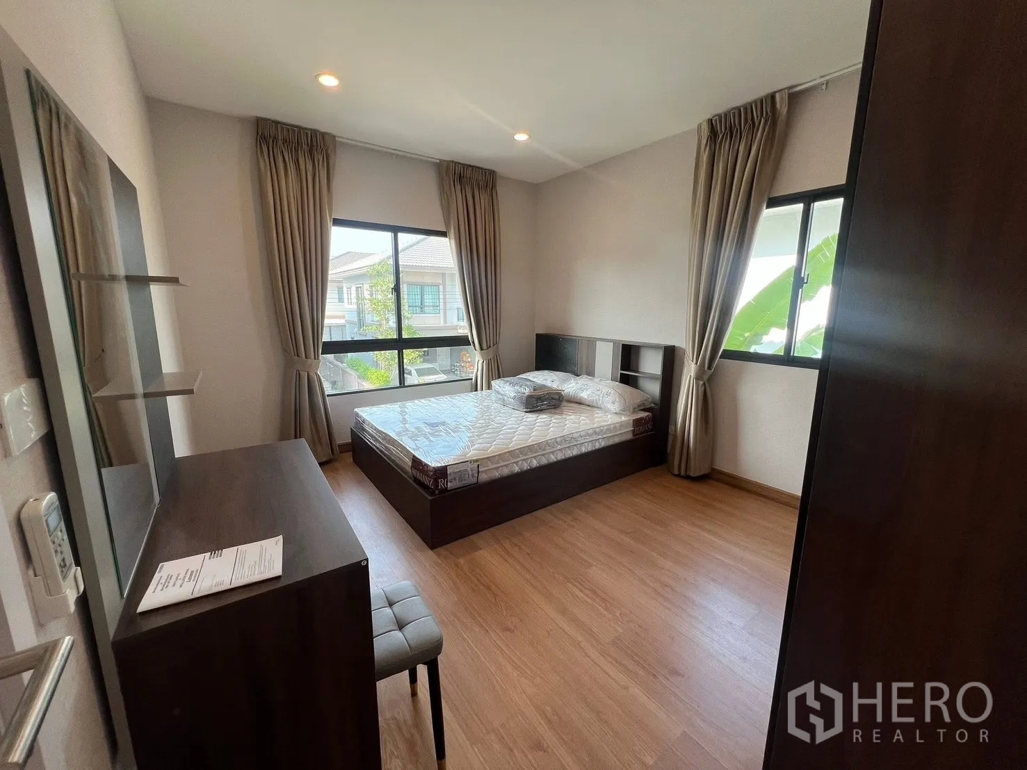 Detached House for rent in Bang Phli, Samut Prakan - Corner bedroom with large windows, bed, desk and wardrobe allowing abundant natural light.