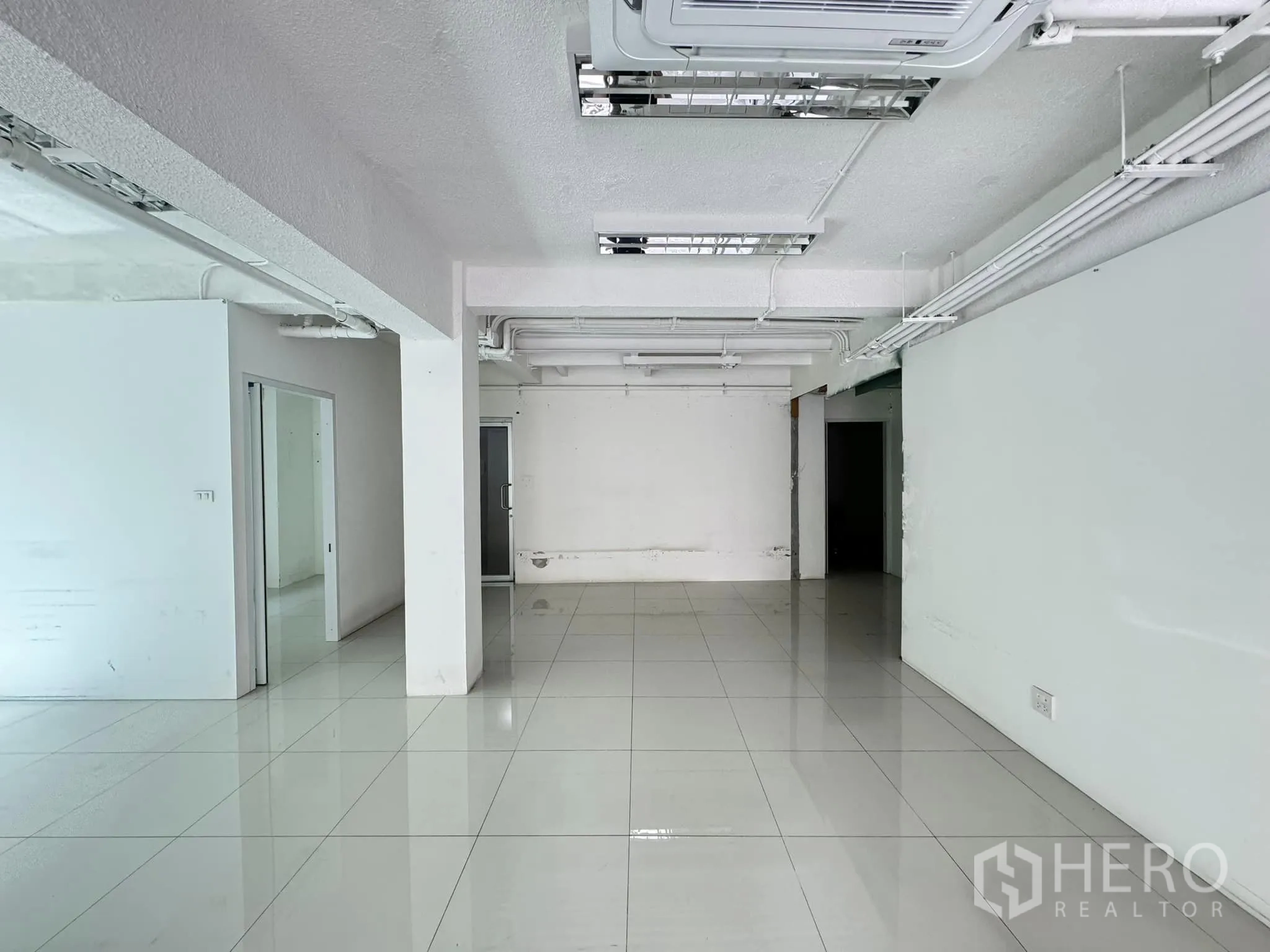 零售空间 出租在Bang Rak, Bangkok - 宽敞的店铺空间，白墙立柱，带玻璃隔间通往后方房间。