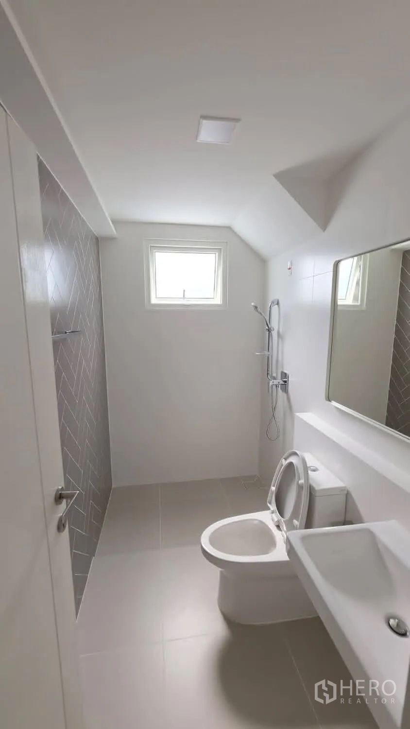 Detached House for rent in Bang Phli, Samut Prakan - Bright bathroom with window, toilet, sink, and open shower with herringbone tile.
