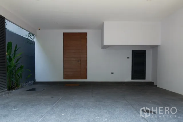 联排别墅 出租在Watthana, Bangkok - 双车位车棚，木质入户门与储物壁龛。