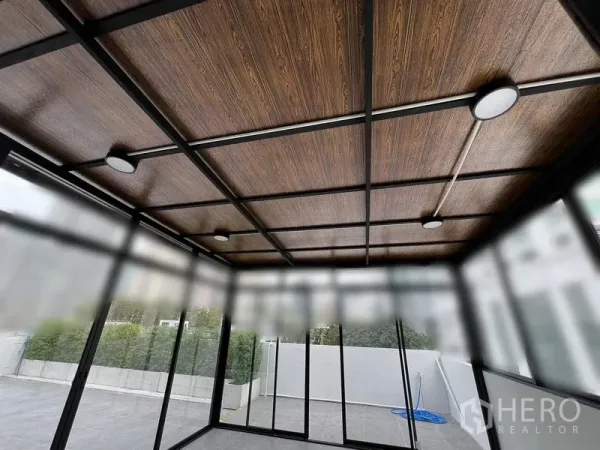 พื้นที่ขายปลีก ให้เช่าในWatthana, Bangkok - ภาพระยะใกล้ของฝ้าไม้ลายพร้อมไฟดาวน์ไลท์ภายในห้องกระจก.