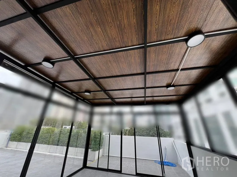 พื้นที่ขายปลีก ให้เช่าในWatthana, Bangkok - ภาพระยะใกล้ของฝ้าไม้ลายพร้อมไฟดาวน์ไลท์ภายในห้องกระจก.
