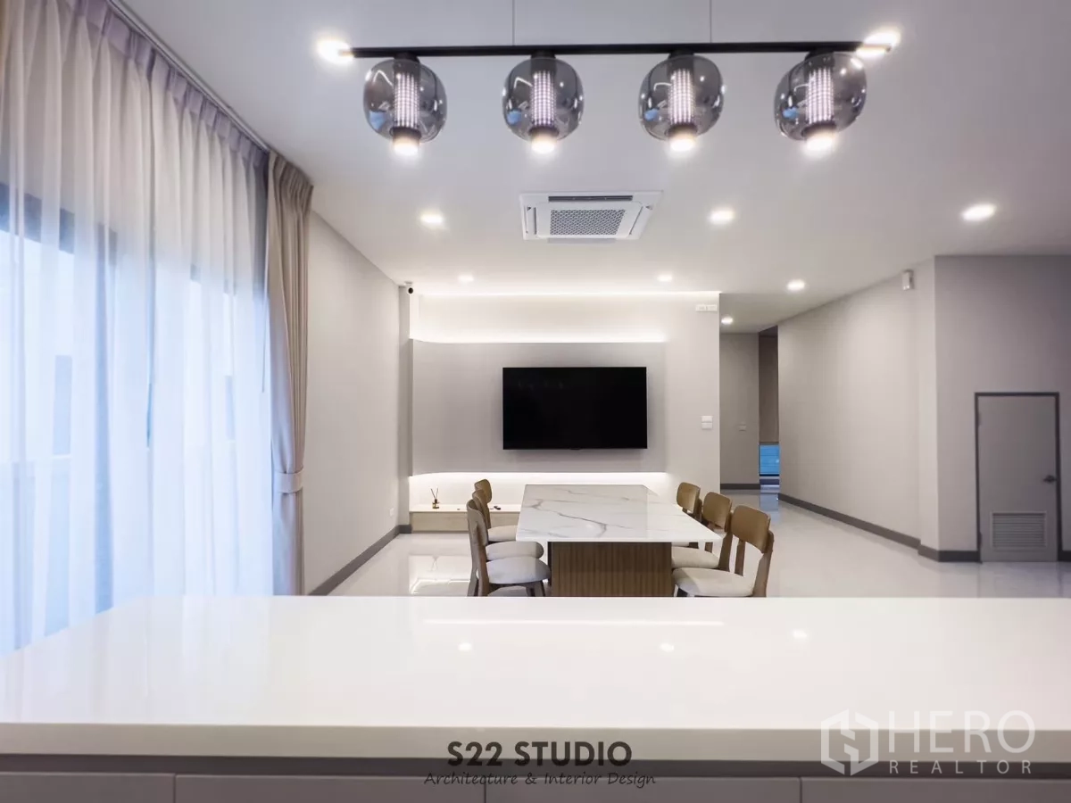 Detached House for rent in Bang Phli, Samut Prakan - Dining area with marble-top table and pendant lights connecting to a bright living space with TV.