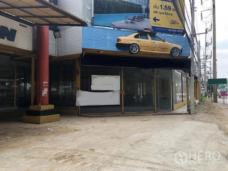 零售空间 出租或出售在Bang Khen, Bangkok - 转角单元门面，卷闸门与屋顶招牌框架。