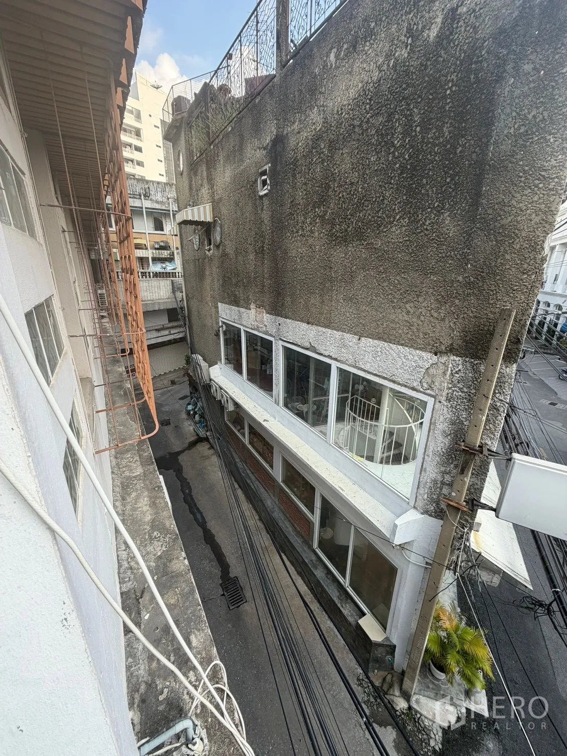 Shophouse for rent in Watthana, Bangkok - View down a narrow alley from an upper floor between neighboring buildings.