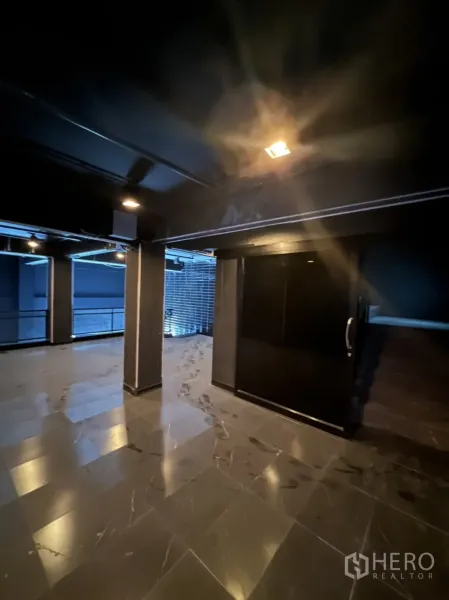 Home Office for rent or sale in Khlong Toei, Bangkok - Corner floor area with pillars, black walls, glass balustrade and a solid door.