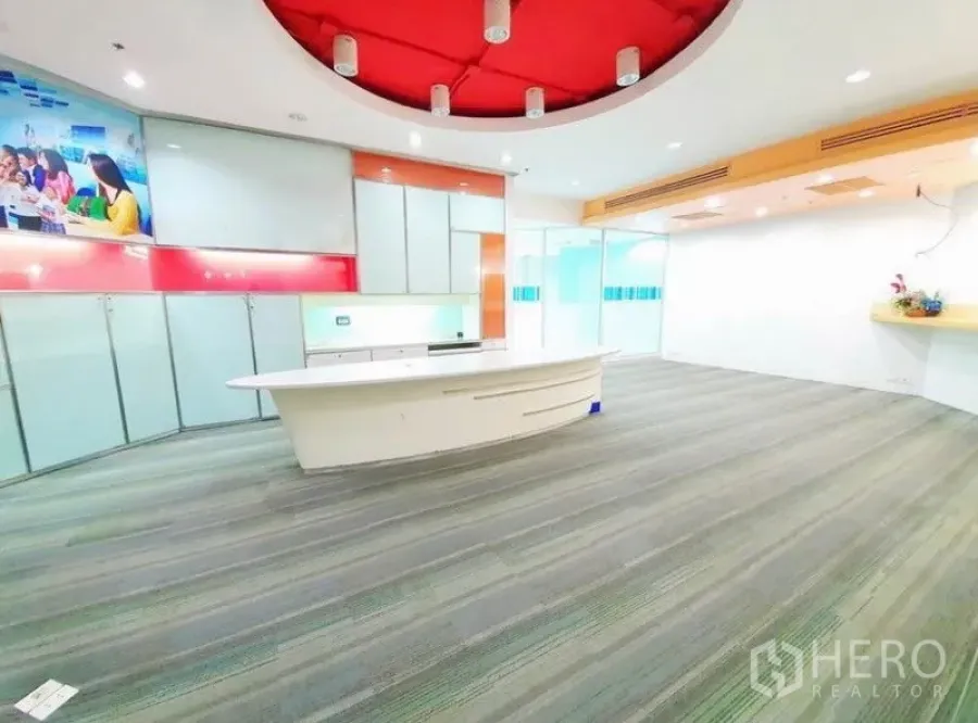 办公空间 出租在Bang Na, Bangkok - 宽敞接待区，白色弧形前台、红色圆形吊顶与地毯地面。