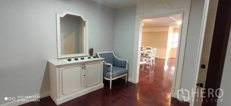 คอนโด ให้เช่าในWatthana, Bangkok - โถงทางเข้ามีตู้คอนโซลสีขาว กระจก และเก้าอี้สีฟ้าบนพื้นไม้ขัดเงา