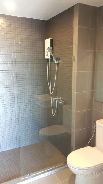 Condominium for rent in Samut Prakan - Modern bathroom with glass-enclosed shower, water heater, and neutral tiled walls.
