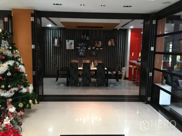 Detached House for rent in Khlong Toei, Bangkok - Formal dining room with long table, upholstered chairs and pendant lighting, opened with folding glass doors.