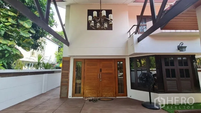 Detached House for rent in Saphan Sung, Bangkok - Front facade with double wooden entry doors and a balcony chandelier above.